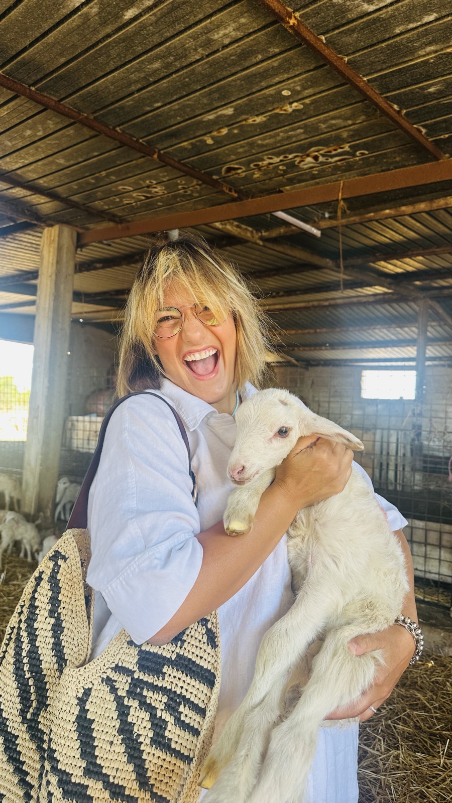 Josephine Ingoglia laughing, holding a lamb at a shepherd's farm in Sicily